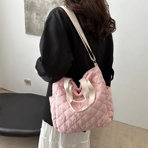 Pink quilted tote bag with diamond pattern and cream adjustable strap shown on model