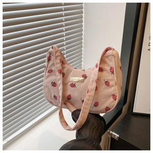 Detailed close-up of pink corduroy hobo bag with red strawberry prints and metal logo
