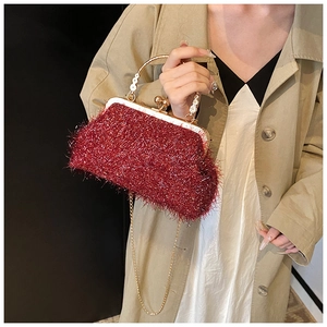 Détail du sac de soirée bordeaux avec texture pelucheuse et poignée en métal fleuri