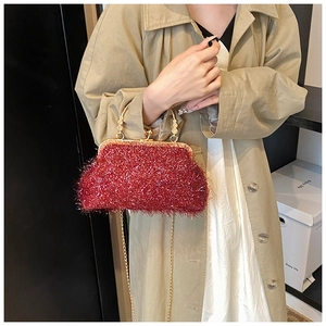 Détail d'un sac de soirée rouge scintillant avec poignée dorée et bandoulière chaîne