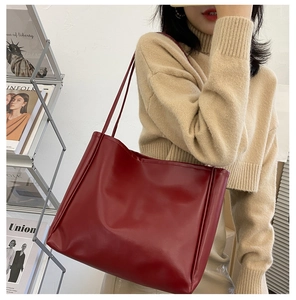 Detailed view of the large deep red leather tote bag being worn by a fashion model