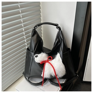 Detail of black PU leather tote bag featuring a cute white plush puppy and side pocket
