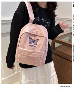 Detail of pink backpack featuring purple butterfly print and Dreams embroidery on pocket