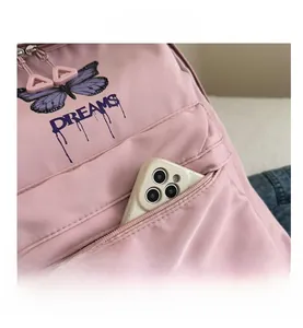 Detail of pink backpack front pocket with purple butterfly print and phone storage space
