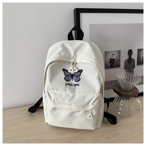 White nylon backpack featuring a purple butterfly print and Dreams text in a cozy setting