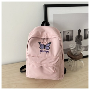 Pink canvas backpack with purple butterfly prints and double zipper detail on a desk
