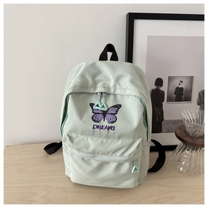 Detail of mint green school backpack featuring butterfly print and DREAMS text design