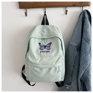Detail of mint green canvas backpack featuring purple butterfly embroidery and Dreams logo