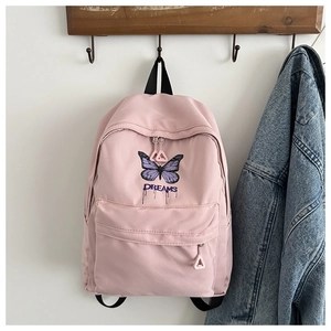 Detailed view of pink school backpack featuring a butterfly print and Dreams lettering