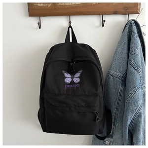 Detail of a black canvas backpack featuring a purple butterfly and DREAMS print detail