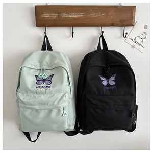 Detail of cute school backpack showing embroidered butterfly and dreams text on nylon fabric