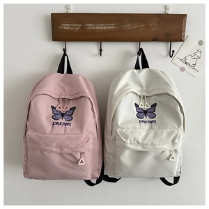 Detail of pink and beige backpacks with butterfly prints and DREAMS art typography