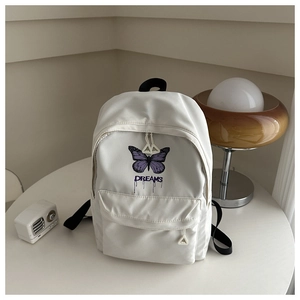 Detailed view of white nylon backpack featuring purple butterfly print and DREAMS text