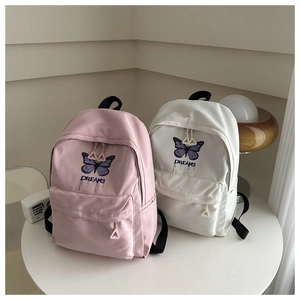 Detail view of pink and white school backpacks with butterfly print on a white table