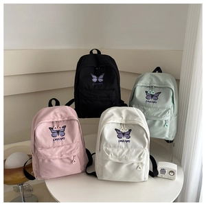 Detail view of four colorful school backpacks with butterfly prints on a white table