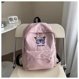 Detail of pink school backpack featuring a purple butterfly print and DREAMS slogan