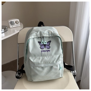 Detail view of mint green backpack with butterfly print and DREAMS text on a chair