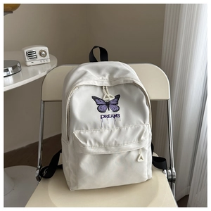 Detail view of the cream school backpack with purple butterfly print and DREAMS text