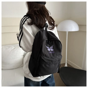 Back view of a girl wearing a black school backpack with purple butterfly prints