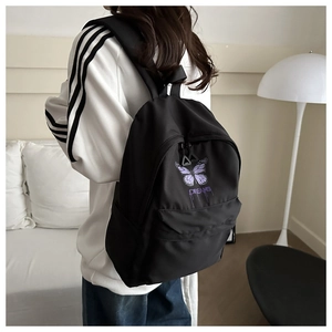 Close-up of a black school backpack with a purple butterfly print and triangle zippers