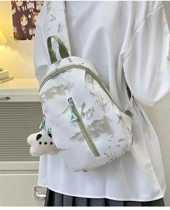 Detalle de bandolera de nailon blanco con estampado de paisaje verde y colgante de panda