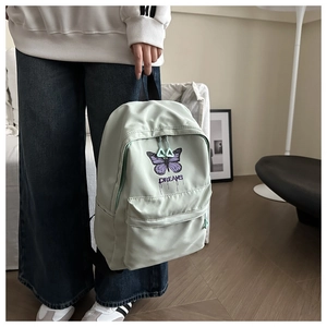 Close-up of a mint green school backpack featuring purple butterfly and Dreams embroidery