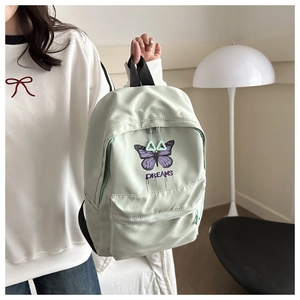 Close-up of mint green backpack with purple butterfly print and DREAMS text detail