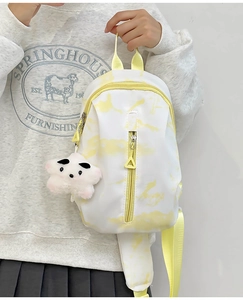 Detalle de mini mochila tie-dye amarillo con correa ajustable y colgante de estrella