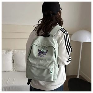 Detailed view of mint green nylon backpack with purple butterfly and dreams embroidery