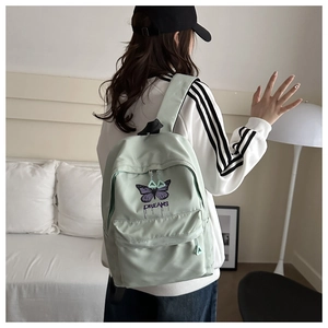 Detail of mint green school backpack featuring purple butterfly embroidery and DREAMS text
