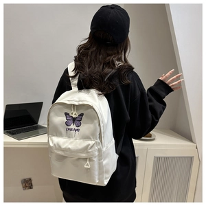 Close-up of a white canvas school backpack featuring purple butterfly embroidery and DREAMS text