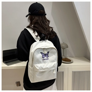 Detailed view of white backpack featuring purple butterfly print and DREAMS graphic text