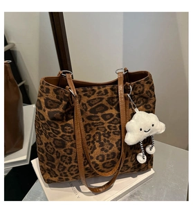 Détail d'un sac cabas léopard avec anses en cuir marron et un charm en peluche nuage