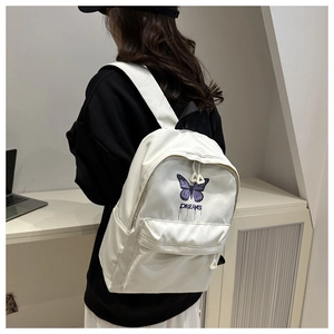 Close-up of white backpack with purple butterfly print and Dreams text embroidery
