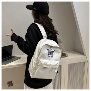 Detailed side view of a white school backpack with butterfly embroidery and Dreams print