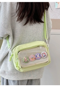 Detail view of light green nylon crossbody bag with cute bunny badges in mesh pocket