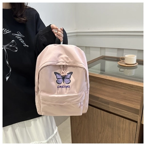 Detail of light pink canvas backpack with purple butterfly and DREAMS embroidery