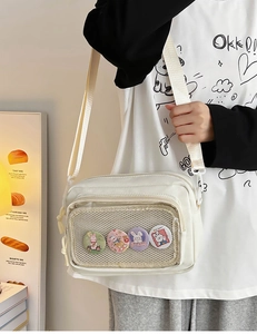 Detail of off-white canvas crossbody bag featuring mesh pocket with four bunny badges