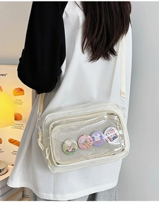 White canvas cross-body bag with clear front pocket and four colorful cartoon bunny pins