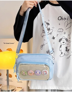 Detail of light blue crossbody bag featuring a transparent window for decorative badges
