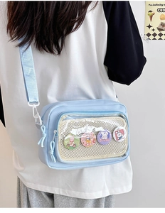 Close-up of light blue canvas ita bag with clear window and cute bunny badges