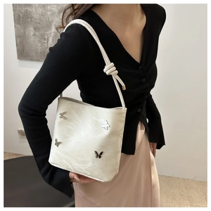 Détail du sac blanc avec breloques papillons argentées et texture de bandoulière nouée