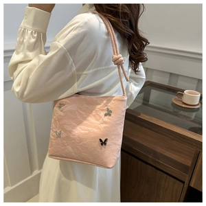 Détail d'un sac à main rose clair avec boucles papillon et bandoulière à nœuds
