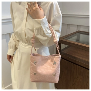 Vue détaillée du sac à main plissé rose orné de papillons décoratifs en métal argenté