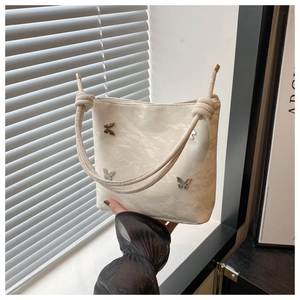 Gros plan du sac plissé crème avec breloques papillons argentées et bandoulière nouée