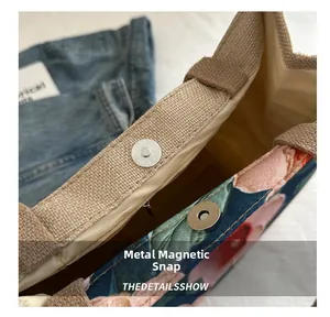 Détail du fermoir magnétique en métal sur un sac cabas en toile à fleurs brodé