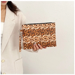 Detalle de bolso de mano con estampado de leopardo, cremallera y correa de muñeca en mano