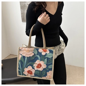 Artistic navy canvas tote bag with pink embossed floral print shown on a model