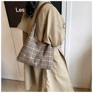 Close-up of houndstooth tote bag with brown leather trim shown on model's shoulder