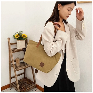 Dettaglio della borsa tote in tela kaki con manici in pelle marrone indossata da modella